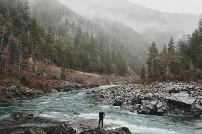 man standing jagged rocks fast-flowing. poster