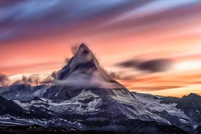 Snowcapped mountain peak cloudy sunrise.