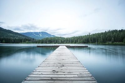 long wooden pier smooth lake. poster