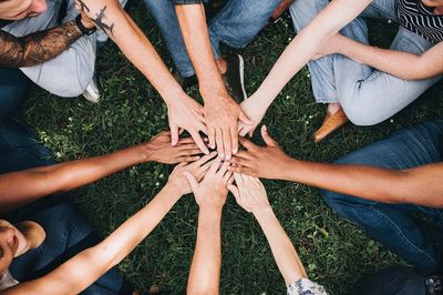 People stacking hands together park. poster
